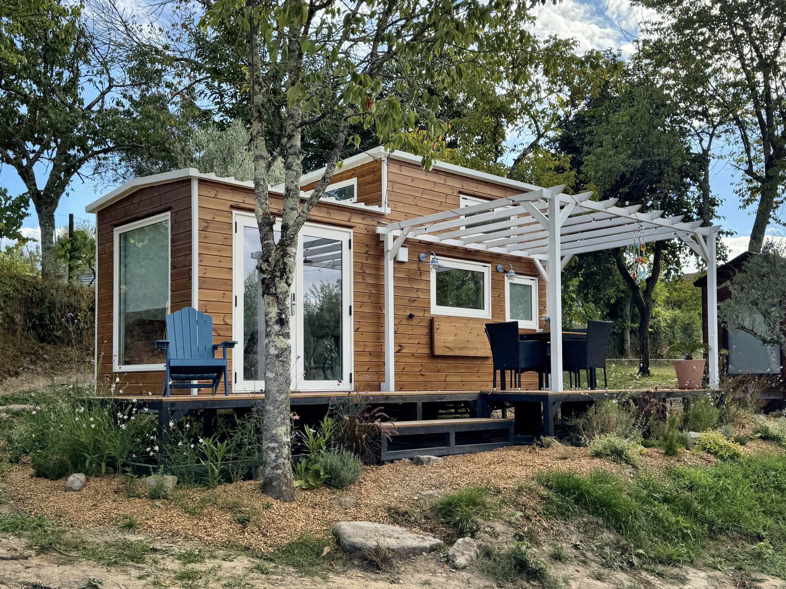 La pequeña casa Grecia en Tiny Escape con una terraza de madera privada rodeada de árboles y naturaleza.